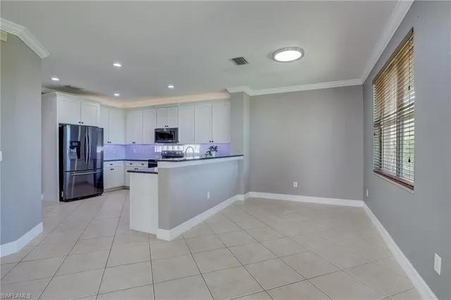 a room with stainless steel appliances kitchen island granite countertop a refrigerator and a stove top oven