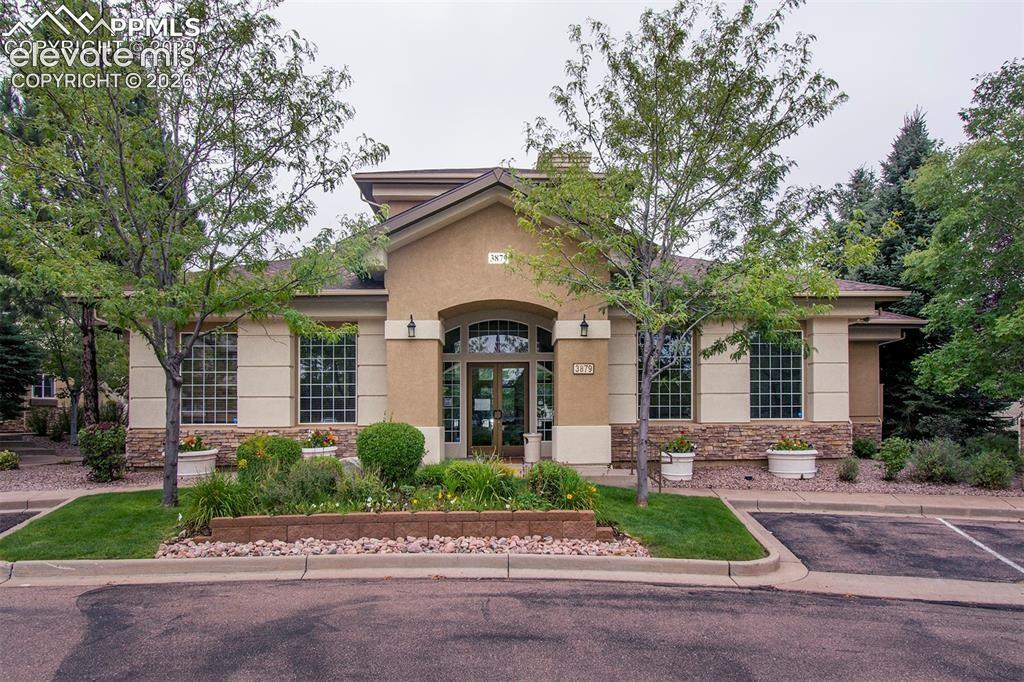 3715 Riviera Grove, Unit 101 Colorado Springs, CO 80922 - Photo 4 of 36 Stucco and stone facade building with arched entry, grid-pattern windows, and landscaped front beds