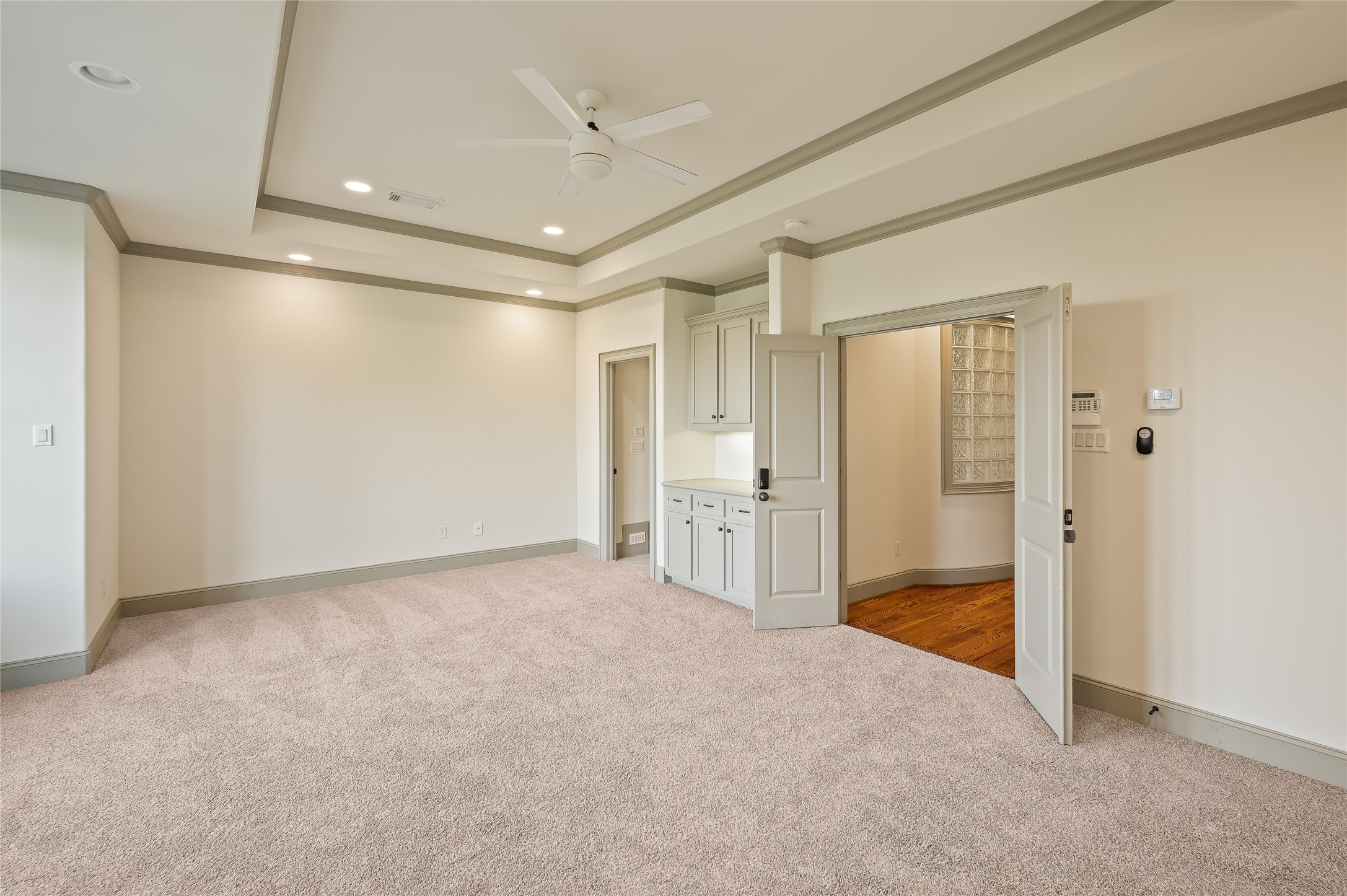 1655 Castle Court Houston, TX 77006 - Photo 25 of 32 Your retreat awaits behind the French doors! This 3rd floor primary bedroom is filled with natural light, and all the extras: tray ceiling, recessed lighting, ceiling fan, new carpet and a coffee bar that you absolutely need.
