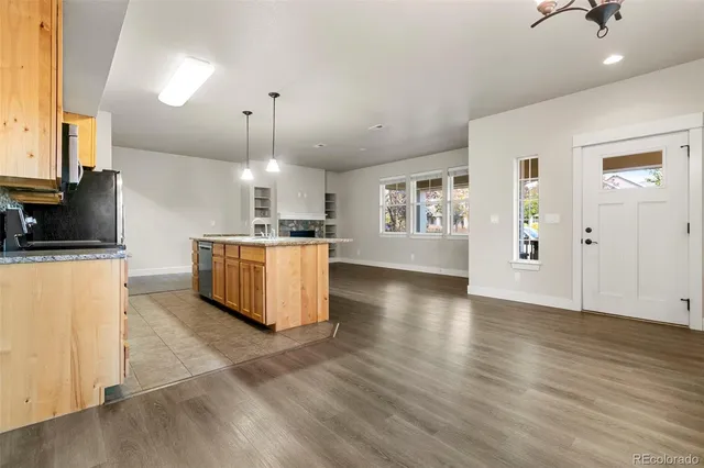 a kitchen with stainless steel appliances granite countertop a stove a refrigerator a oven and a fireplace with wooden floor