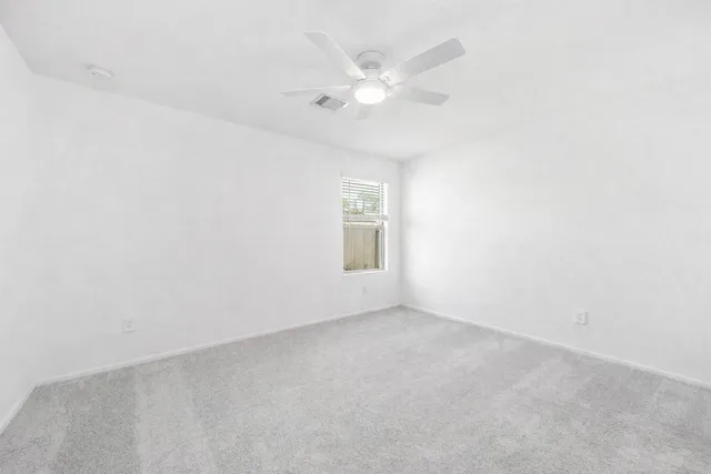 an empty room with a window and a ceiling fan
