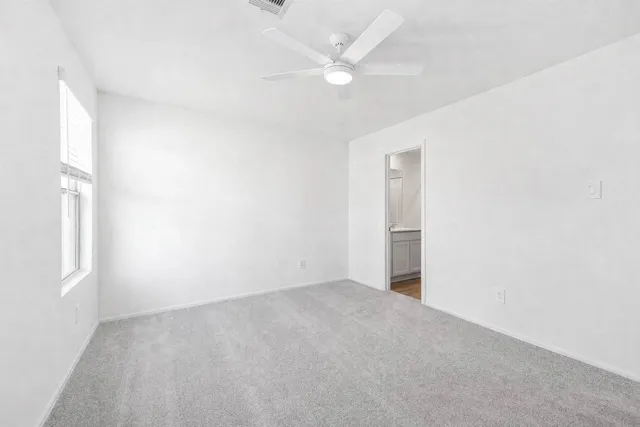 an empty room with a ceiling fan and a window