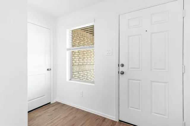 an empty room with wooden floor closet and windows