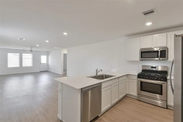 a kitchen with white cabinets and stainless steel appliances