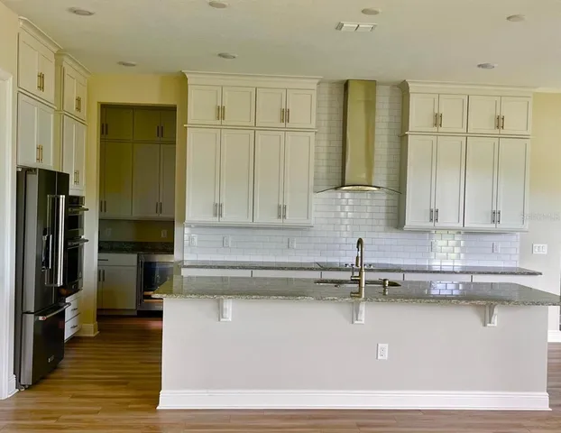 a kitchen with kitchen island granite countertop a sink a counter space stainless steel appliances and cabinets
