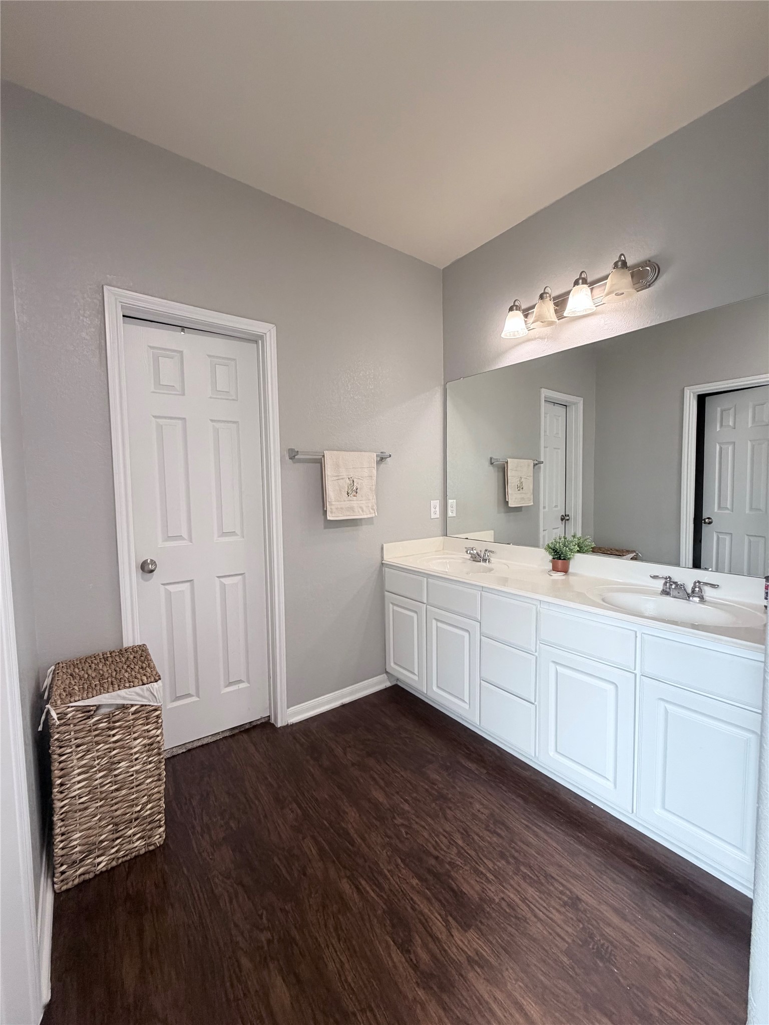 3226 Dappled Vale Trail Spring, TX 77373 - Photo 25 of 26 This bathroom features a double vanity with white cabinetry, a large mirror, and modern lighting. The space is complemented by modern flooring and neutral gray walls, adding a clean, contemporary feel.
