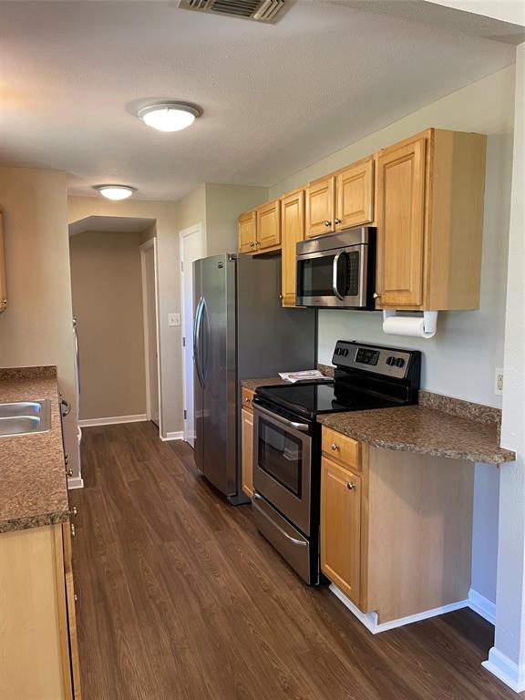 1509 Mitchell Drive Bonham, TX 75418 - Photo 4 of 9 a kitchen with stainless steel appliances wooden cabinets a stove a microwave and a refrigerator