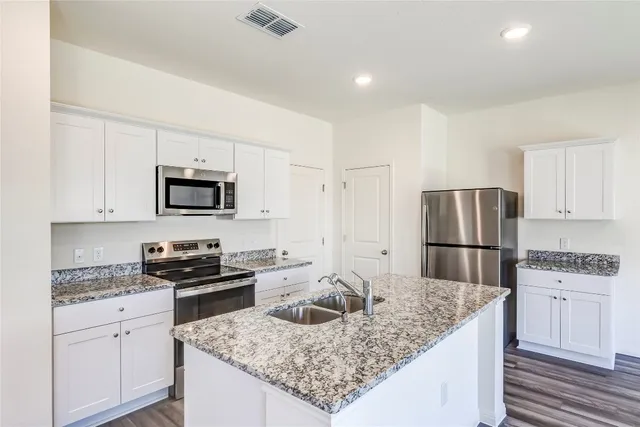 a kitchen with kitchen island granite countertop a sink stove and refrigerator