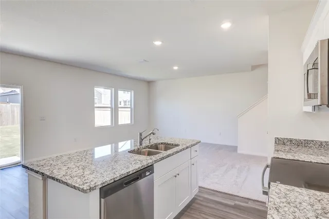a view of a kitchen with a sink refrigerator and wooden floor