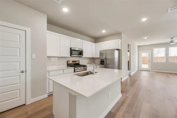 a kitchen with stainless steel appliances a microwave sink refrigerator and cabinets