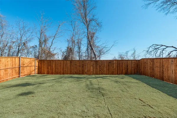 a view of backyard with wooden fence