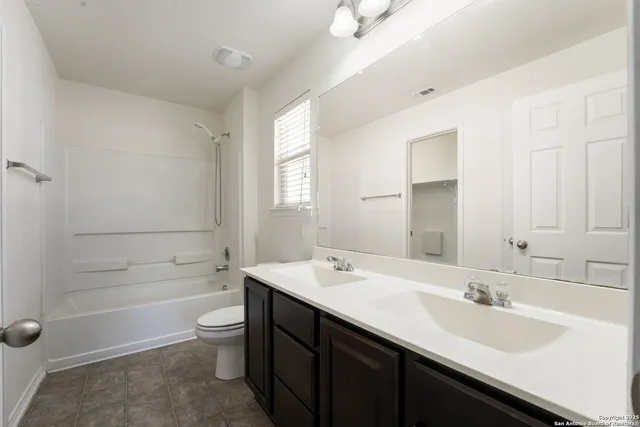 a bathroom with a double vanity sink toilet mirror and bathtub
