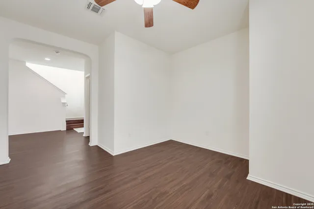 an empty room with wooden floor chandelier fan