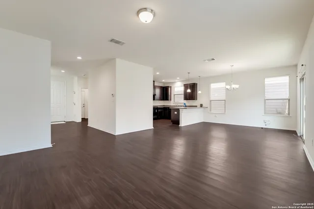 a view of empty room with kitchen and window