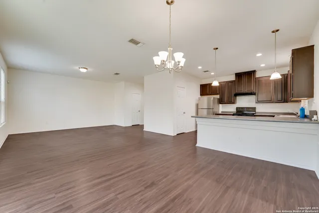 a view of a kitchen with granite countertop a sink dishwasher a refrigerator and a fireplace with wooden floor