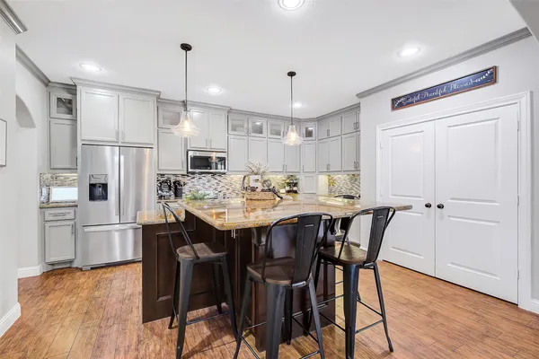a kitchen with stainless steel appliances granite countertop a stove oven a sink dishwasher and white cabinets with wooden floor