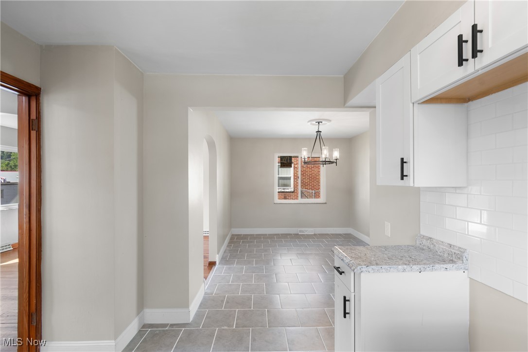 56321-56323 Riley Road Bridgeport, OH 43912 - Photo 11 of 40 Kitchen with a chandelier, white cabinets, pendant lighting, light tile patterned floors, and backsplash