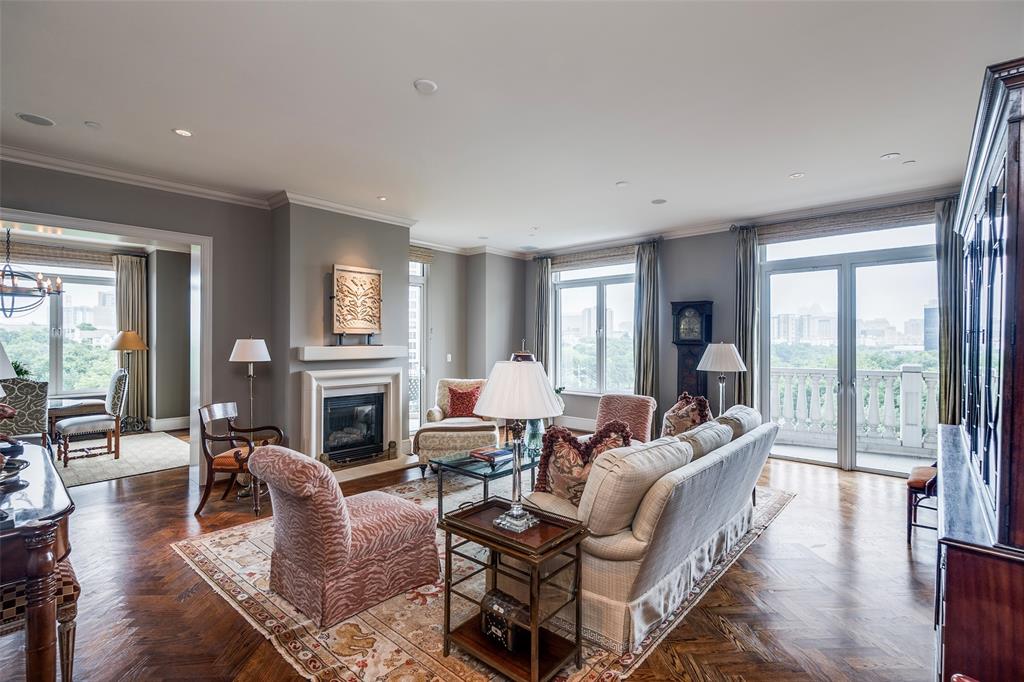 Living room with ornamental molding, plenty of natural light, a glass covered fireplace, a chandelier, and recessed lighting