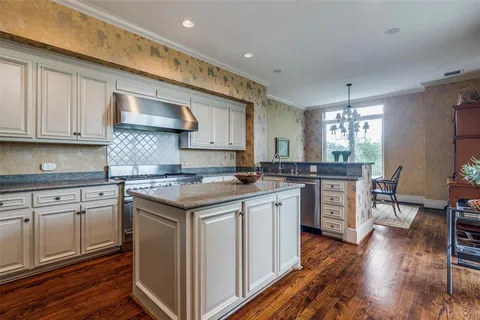 a kitchen with a sink stove cabinets and wooden floor