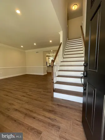 an entryway in a hall with wooden floor and stairs