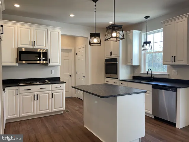 a kitchen with stainless steel appliances granite countertop a sink a stove and a wooden floors