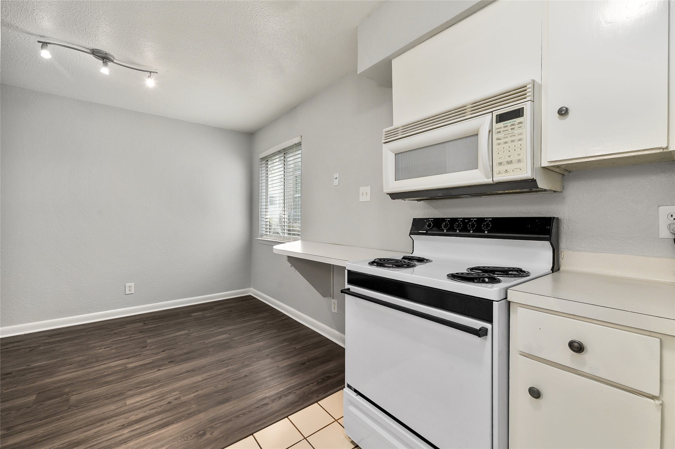2408 Longview Street, Unit 113 Austin, TX 78705 - Photo 12 of 23 Kitchen featuring white appliances, light countertops, a textured ceiling, white cabinets, and light tile patterned flooring