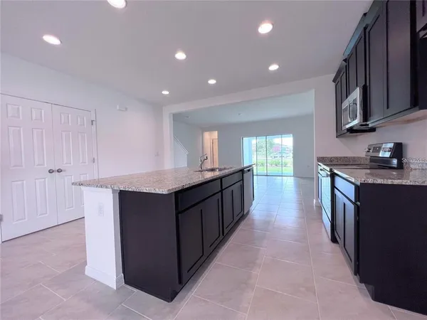 a kitchen with kitchen island granite countertop a sink and dishwasher a oven with wooden cabinets