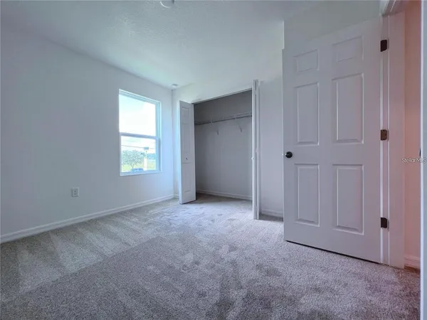 a view of an empty room with closet and a window