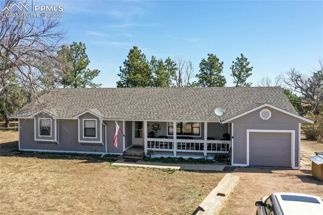 a view of a house with a large window and a yard with plants