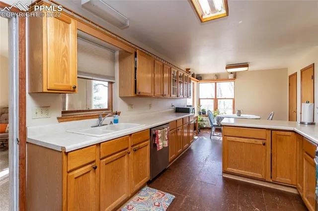 a kitchen with stainless steel appliances granite countertop a stove top oven a sink dishwasher a refrigerator and white cabinets with wooden floor