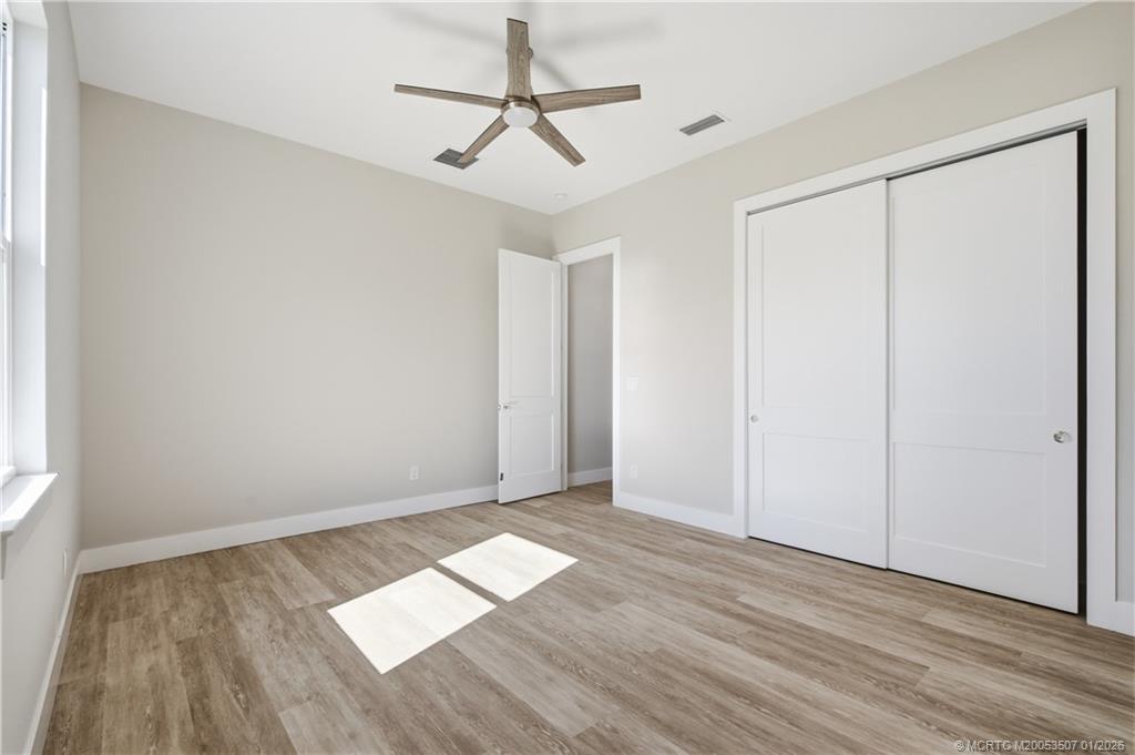 1063 Northwest 12th Terrace Stuart, FL 34994 - Photo 32 of 42 a view of empty room with wooden floor and fan