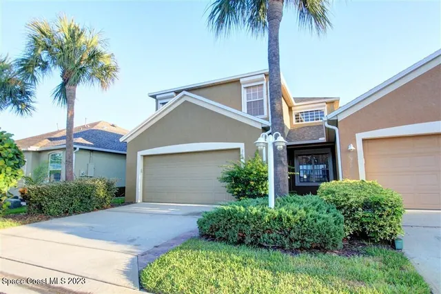 front view of a house with a yard and palm trees