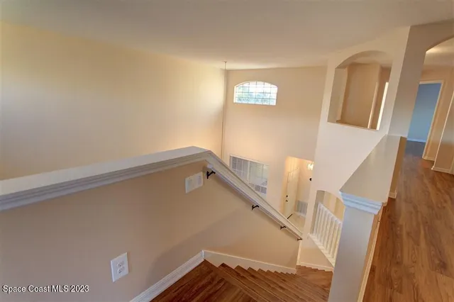 a view of stairs and an empty room with wooden floor