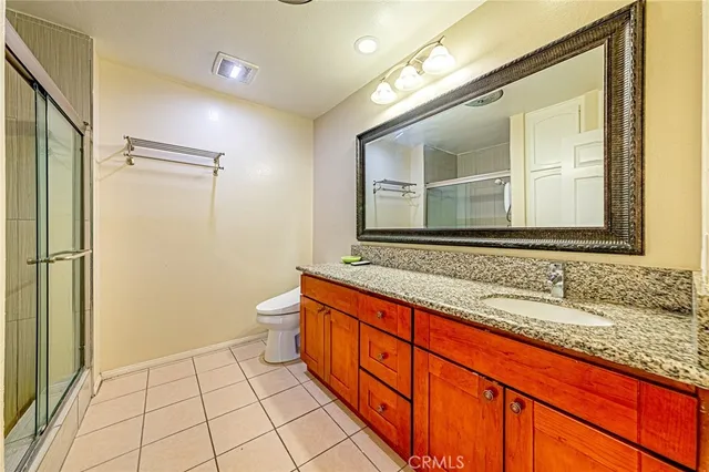 a bathroom with a granite countertop sink mirror and a toilet