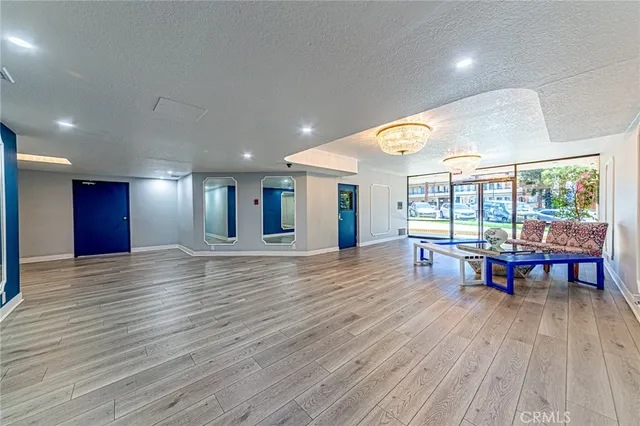 a view of an empty room with wooden floor and a mirror