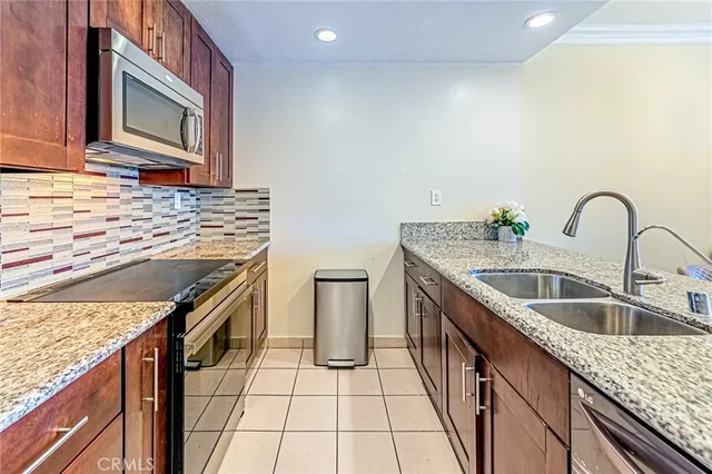 a kitchen with granite countertop a sink a stove top oven and cabinetry
