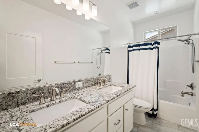 a bathroom with a granite countertop sink a mirror and a bathtub