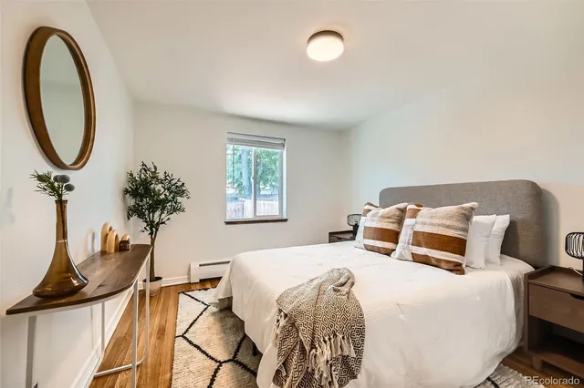 a bedroom with a bed and a potted plant on the dresser