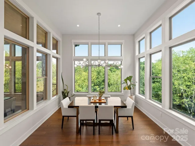 a dining room with wooden floor a chandelier a glass table and chairs