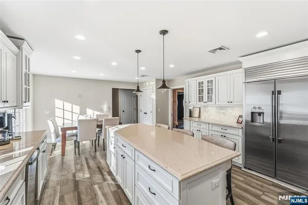 a kitchen with stainless steel appliances a table chairs refrigerator and cabinets