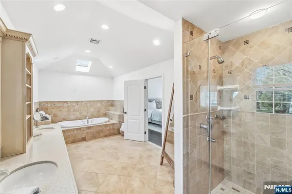 a bathroom with a tub sink shower and mirror