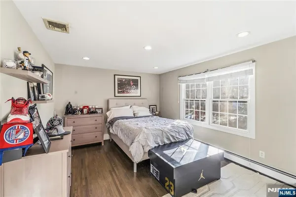 a bedroom with a bed windows and chair