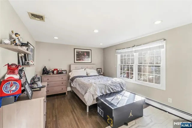 a bedroom with a bed windows and chair