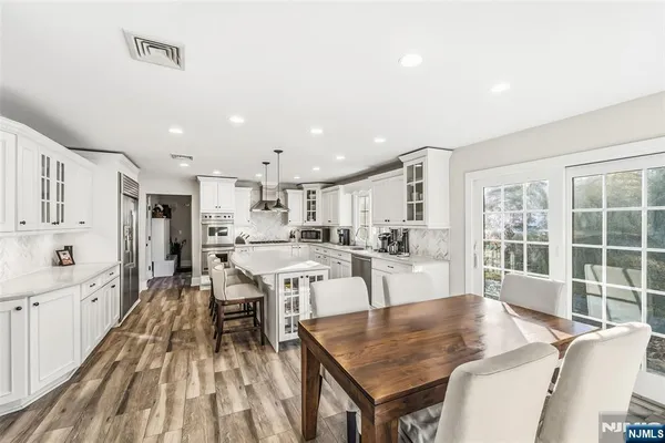 a dining hall with stainless steel appliances granite countertop a stove oven a dining table and chairs with wooden floor