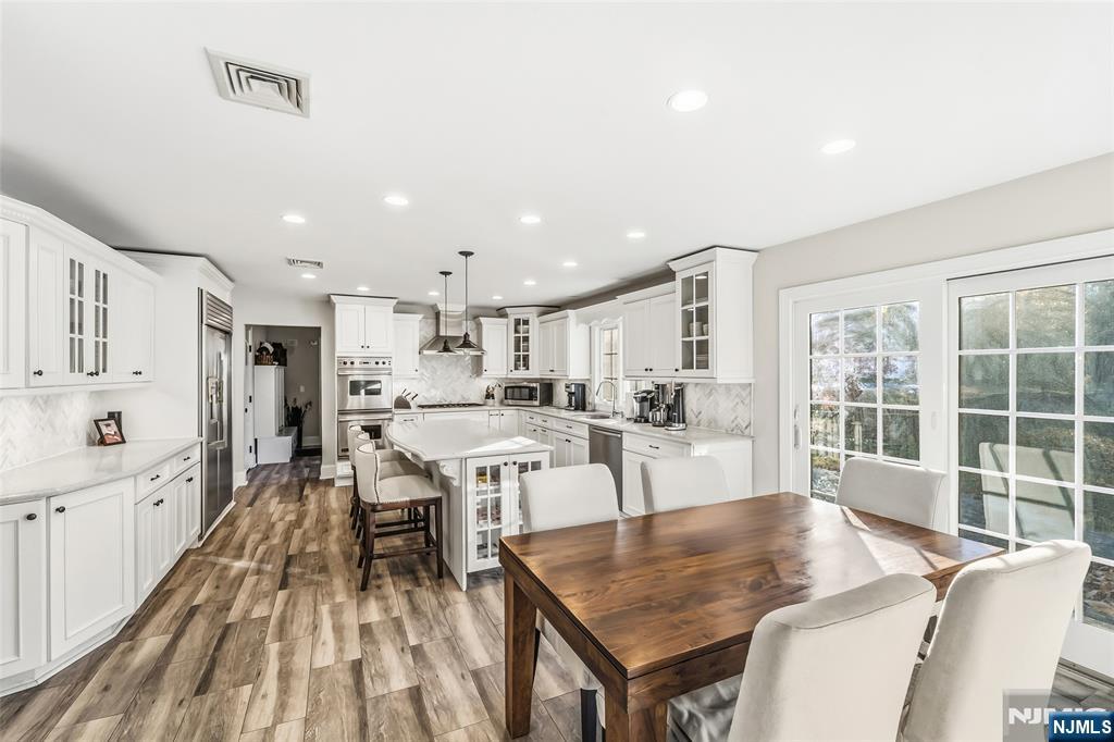 27 Pine Hill Road Old Tappan, NJ 07675 - Photo 9 of 50 a dining hall with stainless steel appliances granite countertop a stove oven a dining table and chairs with wooden floor