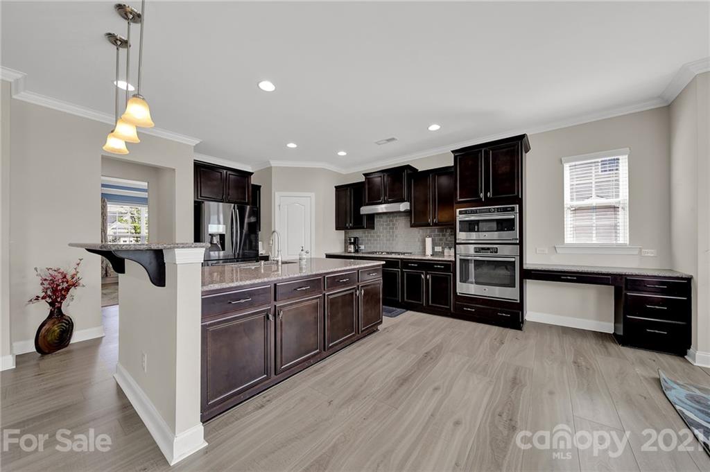 813 Bridge View Court Fort Mill, SC 29708 - Photo 15 of 42 a kitchen with stainless steel appliances kitchen island granite countertop a stove top oven a sink a dining table and chairs with wooden floor