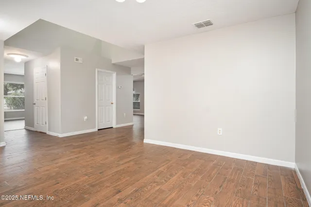 a view of an empty room with wooden floor and a bathroom