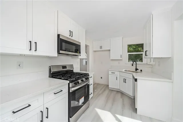 a kitchen with granite countertop a sink a stove and cabinets