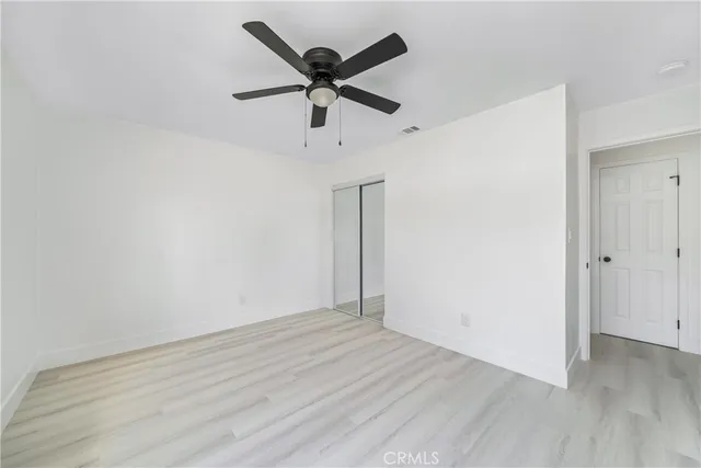 an empty room with wooden floor ceiling fan and window