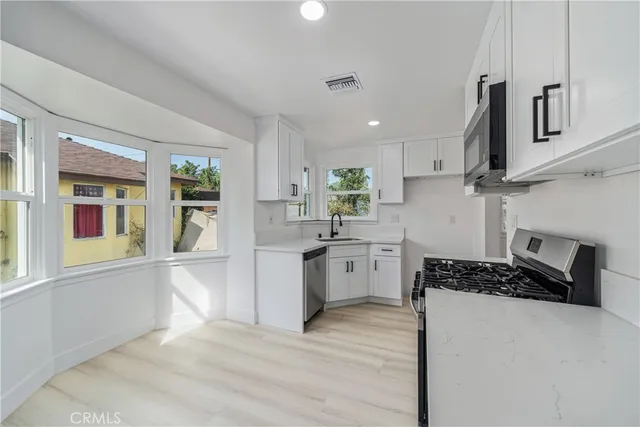 a kitchen with stainless steel appliances granite countertop a stove top oven a sink a counter space and cabinets